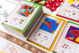 Colorful card game with various cards and dice on a white surface