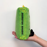 Green plush toy with 'Monster Smash!' text held by a hand on a white background