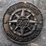 Metallic coin with star design and text 'Every journey begins with a single roll' on a gray surface