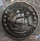 Decorative emblem with ship illustration and text 'Expeditions The Phantom Coast' on a reflective surface.