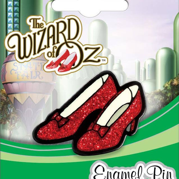 Red glittery shoes enamel pin from 'The Wizard of Oz' on a green and white background with castle illustration.