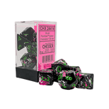 Black and pink polyhedral dice set with green numbers, displayed in front of their packaging.