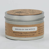 Candle in a tin with 'House of the Witch' label on a light gray background