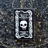 Book titled 'The Little Book of Necromancy' on a starry night sky background