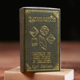 Book titled 'Transmutation' with gold embossed text on a dark background