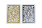 Two decorative playing cards with ornate scrollwork back designs, shown side by side on a plain white background. The left card has a gold and white design, and the right card has a black and white design.