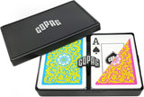 A black playing card deck box shown open on a white background, with one half closed and the other half displaying an Ace of Spades card. The card back design is split between bright blue and pink ornamental patterns, and the box lid has the brand name COPAG in white.