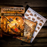 Gloomhaven game components including a book and sticker set on a wooden surface