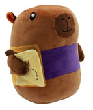 A brown plush toy shaped like a capybara wearing a purple waist belt and holding a yellow patchwork quilt in its paws, isolated on a white background.