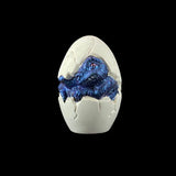 Blue dinosaur figure inside a white egg on a black background
