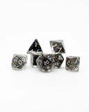 Set of seven polyhedral dice with glittery black and silver faces on a white background