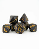Set of black polyhedral dice with gold numbering on a white background