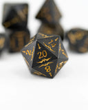 Black polyhedral dice with gold numbering on a white background