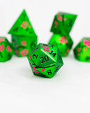Green polyhedral dice with pink floral patterns on a white background