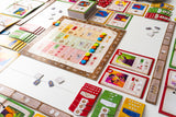Colorful board game with various cards and pieces on a white surface
