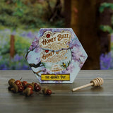 Hexagonal honey packaging with 'Honey Buzz' branding on a wooden surface with decorative elements.