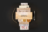Stack of documents labeled 'Family Secrets' with coins and a pen on a dark background