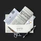 Collection of items including a pen, scissors, and a book titled 'Selstadt Report' on a dark background.