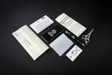 Collection of stationery items including a notebook, pen, scissors, and business cards on a dark background.