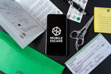 Phone with 'Mobile Escape' app on a desk with papers and scissors
