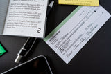 Notebook, pen, and business card on a dark surface