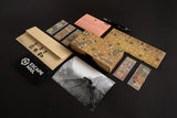 Board game components including cards, a map, and packaging on a dark surface