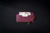 Maroon envelope with documents and a pen on a black background
