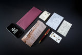 Collection of stationery items including a phone, wallet, cards, and pen on a dark background