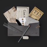Dark gray envelope with stationery items including a pen, pencil, and papers on a black background