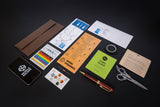 Collection of stationery items including a smartphone, envelope, pen, scissors, and various papers on a dark surface.