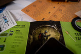 Collection of papers and a magazine with a person on a mountain on a desk.