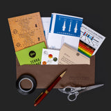 Collection of stationery items including a pen, scissors, and various papers on a dark background.