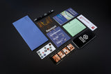 Collection of promotional materials including a blue notebook, pen, business cards, and movie posters on a dark surface.