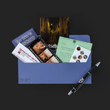Collection of travel-related items including a map, postcard, and pen on a dark background