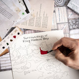 Hand coloring a map of King Haakon Bay with a red marker on a table with other maps and materials.
