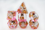 Set of pink and gold polyhedral dice on a white background