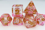 Set of pink and gold dice with floral design on a white background