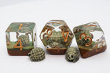 Three transparent resin polyhedral dice with skull-and-ivory number accents, displayed alongside two matching skull-shaped small dice on a white background.