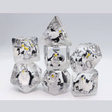A set of transparent polyhedral dice with a penguin print, displayed on a light gray background.