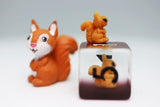 Squirrel-shaped piggy bank with a smaller squirrel figure on top, against a plain background.