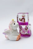 Unicorn figurine next to a transparent container with pink interior on a white background