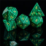 Set of green polyhedral dice with gold numbers on a black background
