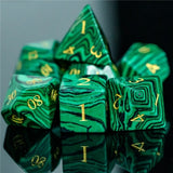 Set of green marbled dice with gold numbers on a reflective surface