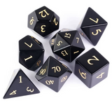 Black polyhedral dice set with gold numbers on a white background