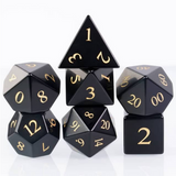 Set of black polyhedral dice with gold numbers on a white background