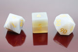 Three polyhedral dice with white faces and yellow numbers on a reflective surface.