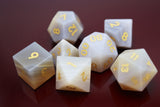 Set of polyhedral dice with gold numbering on a reflective surface