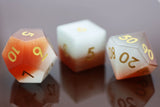 Three polyhedral dice with gradient color and gold numbers on a reflective surface.