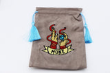Brown drawstring pouch with embroidered design and tassels on a white background
