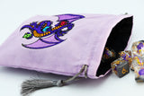 A lavender drawstring pouch with an embroidered purple dragon design, shown with several translucent polyhedral dice spilling out from the open end on a white background.